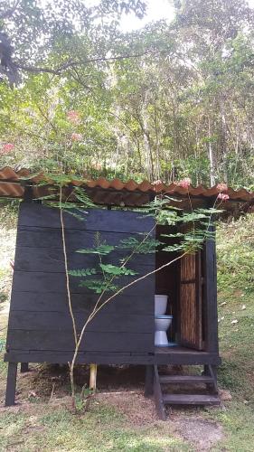 a wooden outhouse with a plant growing out of it at Casita Rio Indio in Nombre de Dios
