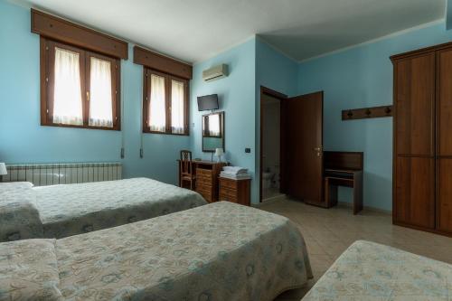 una camera d'albergo con due letti e uno specchio di AlloggiItalia a Porto Tolle