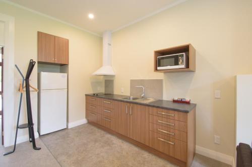 a kitchen with a refrigerator and a microwave at Willowbrook Country Apartments in Arrowtown