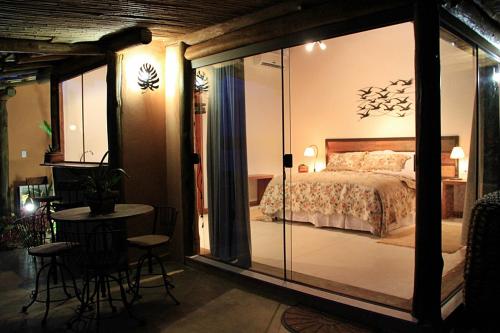 a bedroom with a bed and a table and chairs at Pousada Ecológica Espelho D'Água in Carrancas