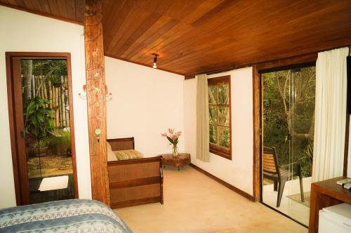 a room with a bed and a desk and windows at Pousada Ecológica Espelho D'Água in Carrancas