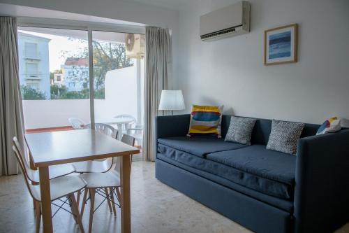 a living room with a blue couch and a table at Apartamentos Dunamar in Vila Nova de Milfontes