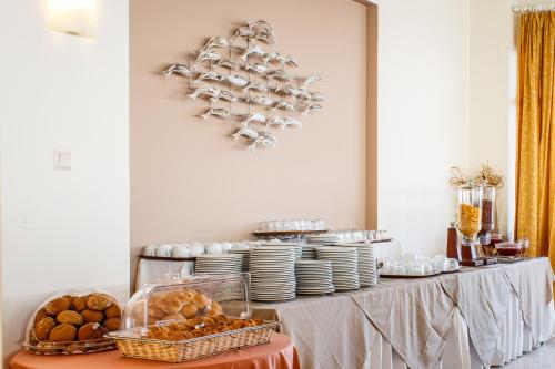 a table with plates and cups and a table with bread at Chryssi Akti Hotel in Argasi