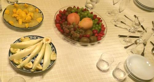 a table with a plate of fruit and a bowl of grapes at Pousada Caminho dos Ipês in Bocaina de Minas