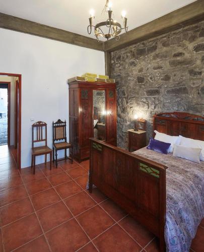 a bedroom with a bed and a stone wall at Casa do Vale do Sossego in Capelas