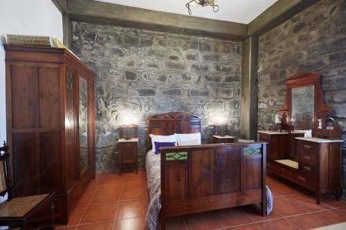 a bedroom with wooden furniture and a stone wall at Casa do Vale do Sossego in Capelas