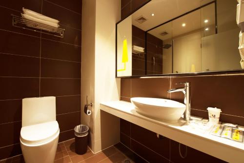 een badkamer met een wastafel, een toilet en een spiegel bij IU Hotel Chongzhou Qinhe Square in Chongzhou