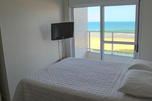 um quarto com uma cama e vista para a praia em Aquarelle Ingleses em Florianópolis