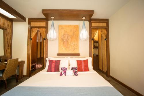 a bedroom with a large white bed with red pillows at Sibsan Resort & Spa Maetaeng Chiang Mai in Mae Taeng
