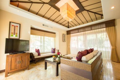 a living room with a couch and a flat screen tv at Sibsan Resort & Spa Maetaeng Chiang Mai in Mae Taeng