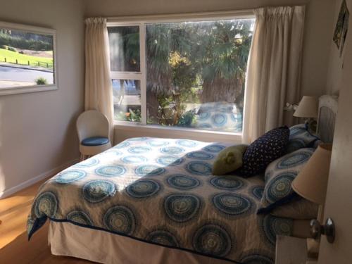 a bedroom with a bed with a large window at Beach Side B & B in Auckland