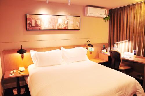 um quarto de hotel com uma cama grande e uma secretária em JinJiang Inn Wujiang Tongli Yunli Bridge em Suzhou
