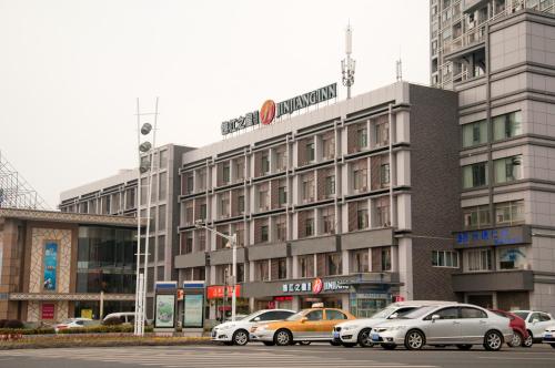a building with cars parked in front of it at JinJiang Inn Wujiang Tongli Yunli Bridge in Suzhou