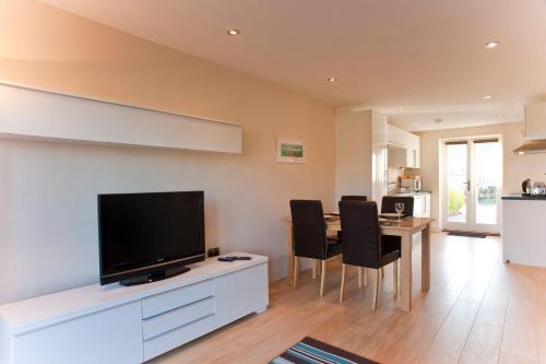 a living room with a television and a table with chairs at Bay Retreat Villas in Padstow
