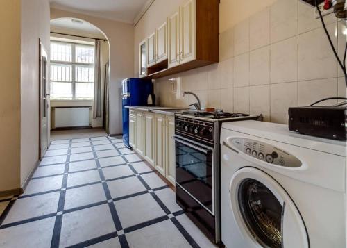 uma cozinha com uma máquina de lavar e secar roupa num piso de azulejo em Apartment on Lysenka 27 em Lviv