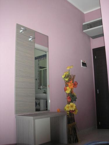 Un baño con espejo y flores en la pared. en Hotel Playa, en Rímini