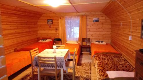a room with three beds and a table in it at Kalamehe Farmstay in Alatskivi