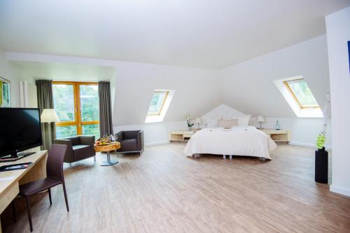 a large white room with a bed and a tv at Sporthotel Fuchsbachtal in Barsinghausen