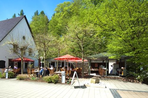 a restaurant with tables and umbrellas next to a building at Sporthotel Fuchsbachtal in Barsinghausen