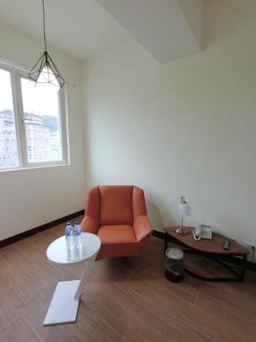 a living room with an orange chair and a table at Long Zhi Yue Hotel in Nangan