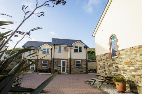 a house with a brick courtyard next to a church at Tregurrian Villas in Newquay