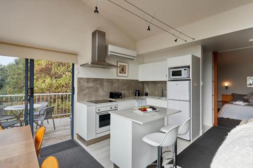 a kitchen with white cabinets and a balcony with a bed at Tamar River Apartments in Rosevears