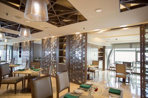a dining room with tables and chairs and a wall of windows at Crowne Plaza Dhaka Gulshan by IHG in Dhaka
