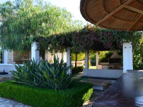 a garden with a patio with a wooden umbrella at Luxury Villa Flora Kiparissia in Kyparissia