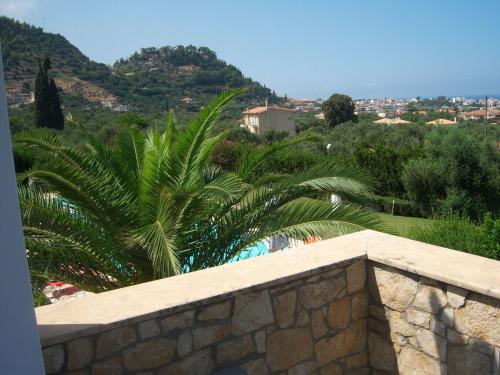 a palm tree sitting next to a stone wall at Luxury Villa Flora Kiparissia in Kyparissia