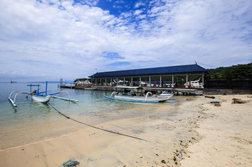 a boat is docked at a dock on a beach at Dewi Villa Padangbai Hotel in Padangbai
