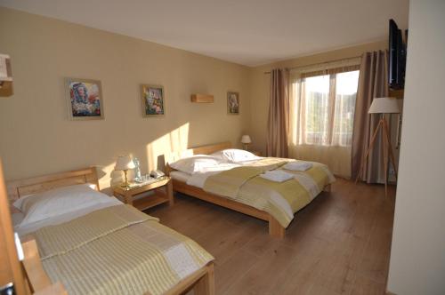 シュチルクにあるJaśminowe Ogrodyのベッド2台と窓が備わるホテルルームです。