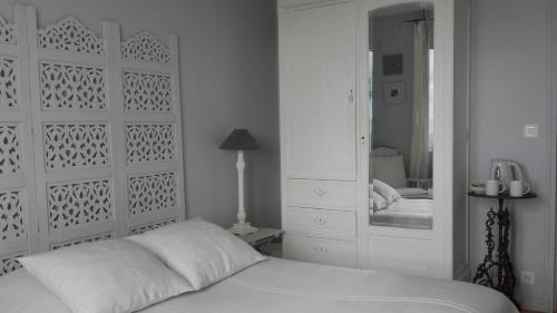 a white bedroom with a bed and a mirror at Chambres d'hôtes Christa in Saint-Pair-sur-Mer
