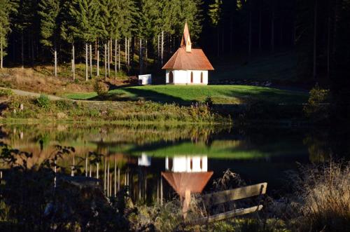 uma pequena capela em cima de um pequeno lago em Pension Sandhof em Knittelfeld