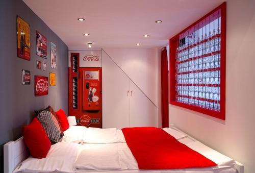 BpR City Center Design Apartments في بودابست: غرفة نوم بسرير احمر وبيض وآلة صودا