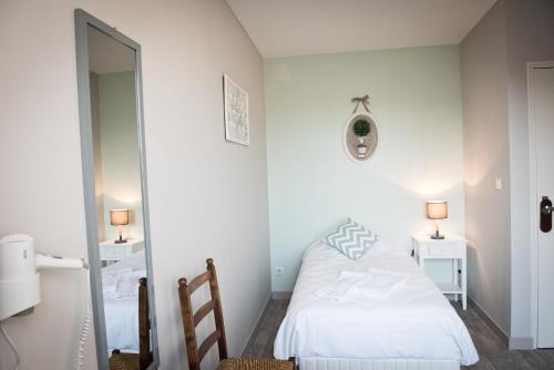 a small bedroom with a bed and a mirror at Logis Hotel Restaurant Le Relais Fleuri in Vervins