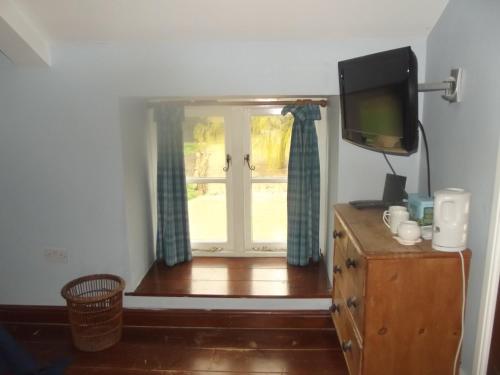 a room with a window and a television on a dresser at Pleck Barn B&B in Ansty