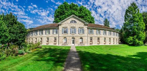 a large stone building with a grass yard at Kurhotel Im Park in Schinznach Bad