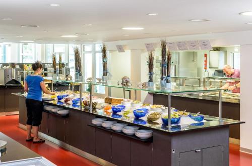 a woman standing in front of a counter with food at Kurhotel Im Park in Schinznach Bad