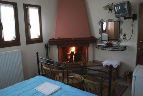 1 dormitorio con chimenea, 1 cama y TV en Guesthouse Xenioti, en Tsagkarada