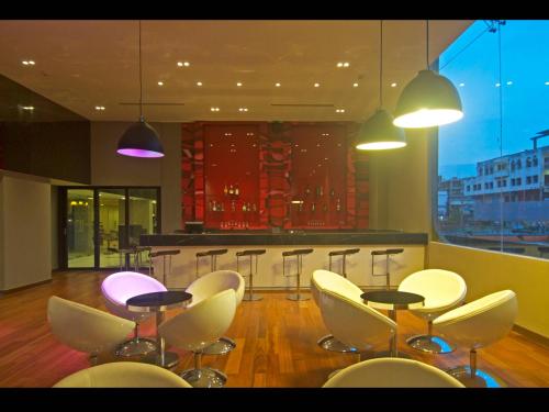 a restaurant with a bar with white chairs and a counter at Keys Select by Lemon Tree Hotels, Visakhapatnam in Visakhapatnam