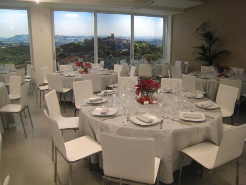 a banquet hall with white tables and chairs and windows at Blu Arena Hotel in Montecchio
