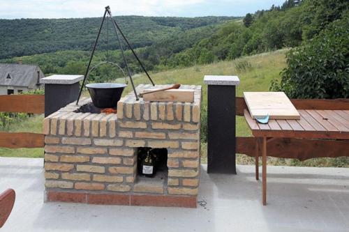 a brick fireplace with a wooden table and a table at Borospince Vendégház in Pécsely