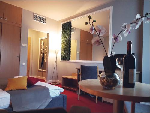 a living room with a couch and a table with a bottle of wine at Hotel Boavista in Timişoara