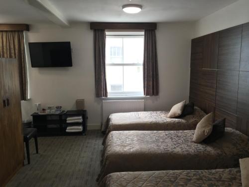 a hotel room with two beds and a television at Brighton Beach Inn in Brighton & Hove