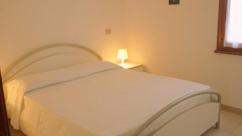 カンニジョネにあるResidenza La Banchinaの白いベッドルーム(ランプ付)の白いベッド1台