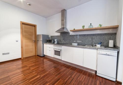 a kitchen with white cabinets and a wooden floor at Anchieta 60 in La Laguna