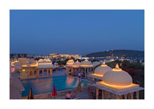 a view of a building with a swimming pool at night at Chunda Palace in Udaipur