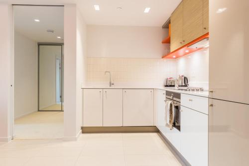 a kitchen with white cabinets and a sink at Royal Style Apartment - 5 mins walk to ExCeL London in London
