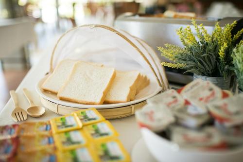 een tafel met een mand met brood en een bord met sandwiches bij Nisasiri Boutique Resort in Laem Sing
