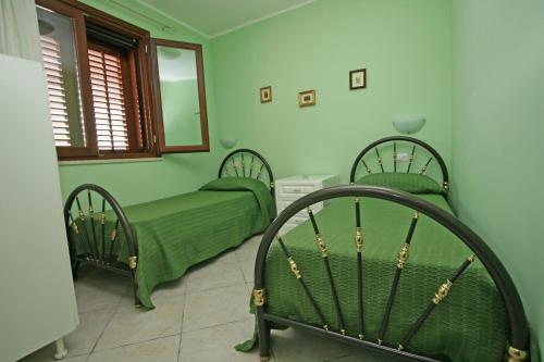 サン・ヴィート・ロ・カーポにあるAppartamento Armonie Verdeのベッドルーム(緑のベッド2台、鏡付)